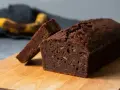 En saftig banankaka i långpanna, med en skiva uppskuren. En övermogen banan ligger i bakgrunden, redo att bli en del av nästa bakverk.