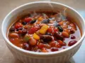 Varm och ångande chili sin carne i en vit skål, full av bönor, tomater och paprika. En härlig vegetarisk rätt.