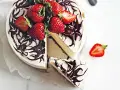 En krämig no bake cheesecake med chokladdrizzle och färska jordgubbar. En bit är uppskuren.