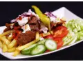 En tallrik med kebab, pommes frites, tomater, gurka, sallad och en grön chili. Perfekt för att inspireras till ett gott kebabsås recept.