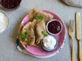 En tallrik med glutenfria pannkakor, serverade med sylt och grädde. En härlig frukost eller fika!