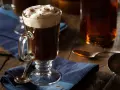 En värmande irish coffee med vispad grädde och kanel på en blå duk.