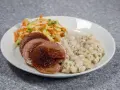 En tallrik med stuvade makaroner, stekt falukorv och en sallad på vitkål och morötter.