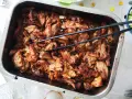 Saftigt, långkokt fläskkött i en ugnsform, perfekt för ett carnitas recept. Tång ligger redo att servera.