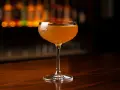 En gyllene Paper Plane cocktail i ett elegant glas, redo att lyfta smaklökarna.