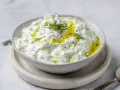 En skål med krämig tzatziki, perfekt för ditt tzatziki recept. Toppad med olivolja och färsk dill.
