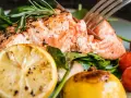 En saftig bit inkokt lax i ugn, serverad med citron, körsbärstomater och färska örter. En härlig måltid!