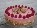 En rosa hallonmousse tårta dekorerad med färska hallon och passionsfrukt. Kanterna är täckta med rostade mandelflagor.