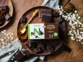 Chokladbitar och en förpackning med Nutrilett Premium Dark Chocolate Bar, en del av deras kalorisnål mat-sortiment.