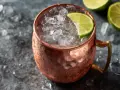En iskall moscow mule i kopparmugg, garnerad med lime och omgiven av is.