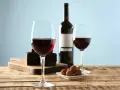 Två glas rött vin, en flaska, chokladpraliner och en bit chokladkaka. En perfekt kombination av vin till choklad.