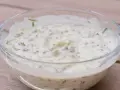 En krämig kall sås till fisk, med kapris och örter, serverad i en glasskål på en träyta.