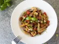 En tallrik med chorizo pasta med grönsaker som paprika, zucchini och champinjoner. Garnerad med färsk basilika och salladslök.