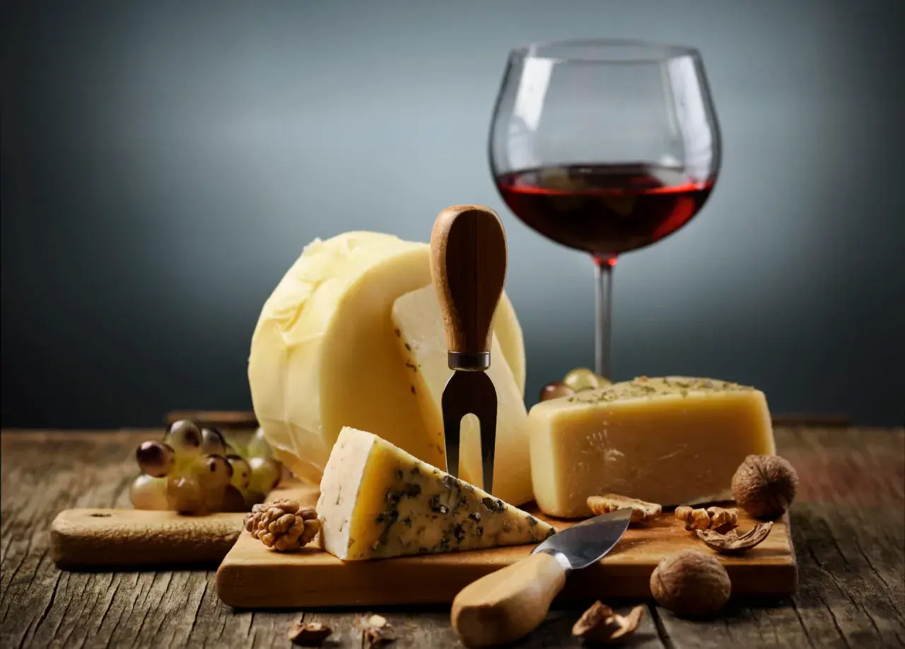 En härlig ost och vinprovning med olika ostar, vindruvor, nötter och ett glas rött vin.