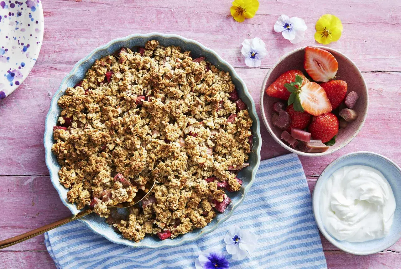 En härlig gammaldags rabarberpaj med krispigt täcke, serverad med färska jordgubbar och grädde. Perfekt sommardessert!