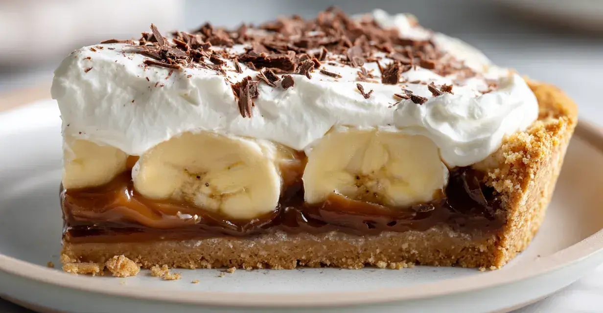 En bit krämig banoffee paj med banan, kolasås, vispgrädde och chokladströssel.