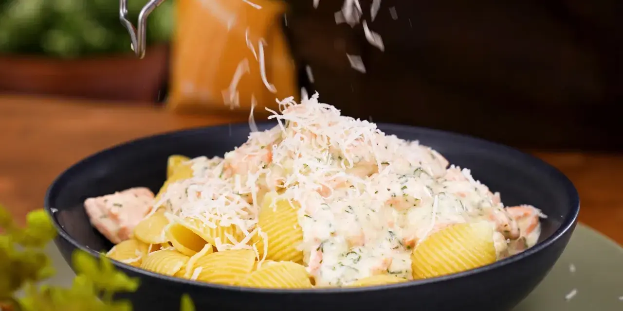 En krämig lax pasta med crème fraîche toppas med riven ost.