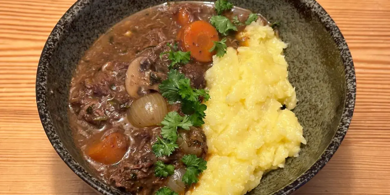 En mustig boeuf bourguignon med möra köttbitar, champinjoner, lök och morötter, serverad med krämigt potatismos.