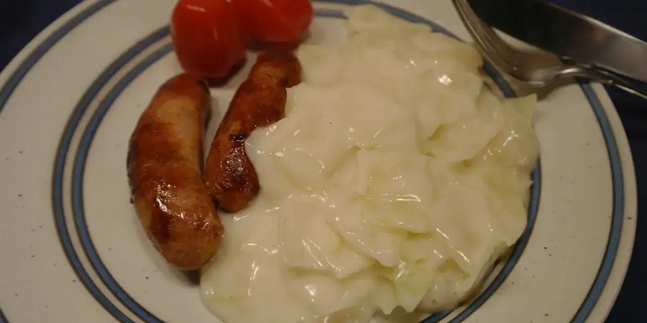 En tallrik med stuvad vitkål, korv och tomater. En klassisk svensk husmanskosträtt.