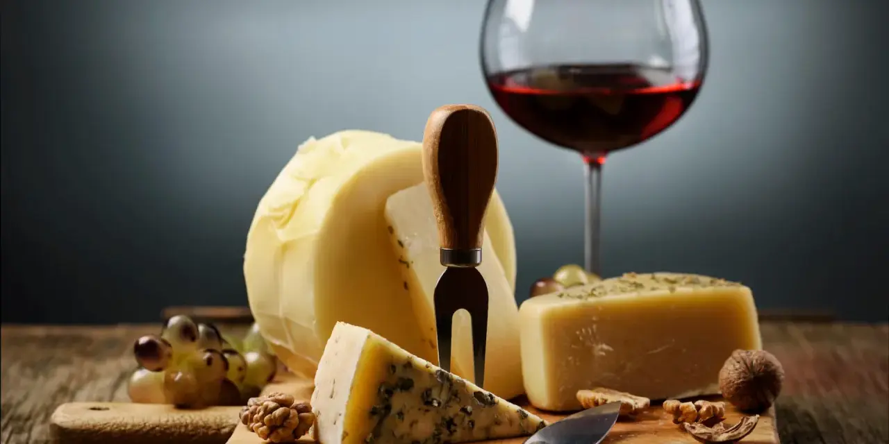 En härlig ost och vinprovning med olika ostar, vindruvor, nötter och ett glas rött vin.
