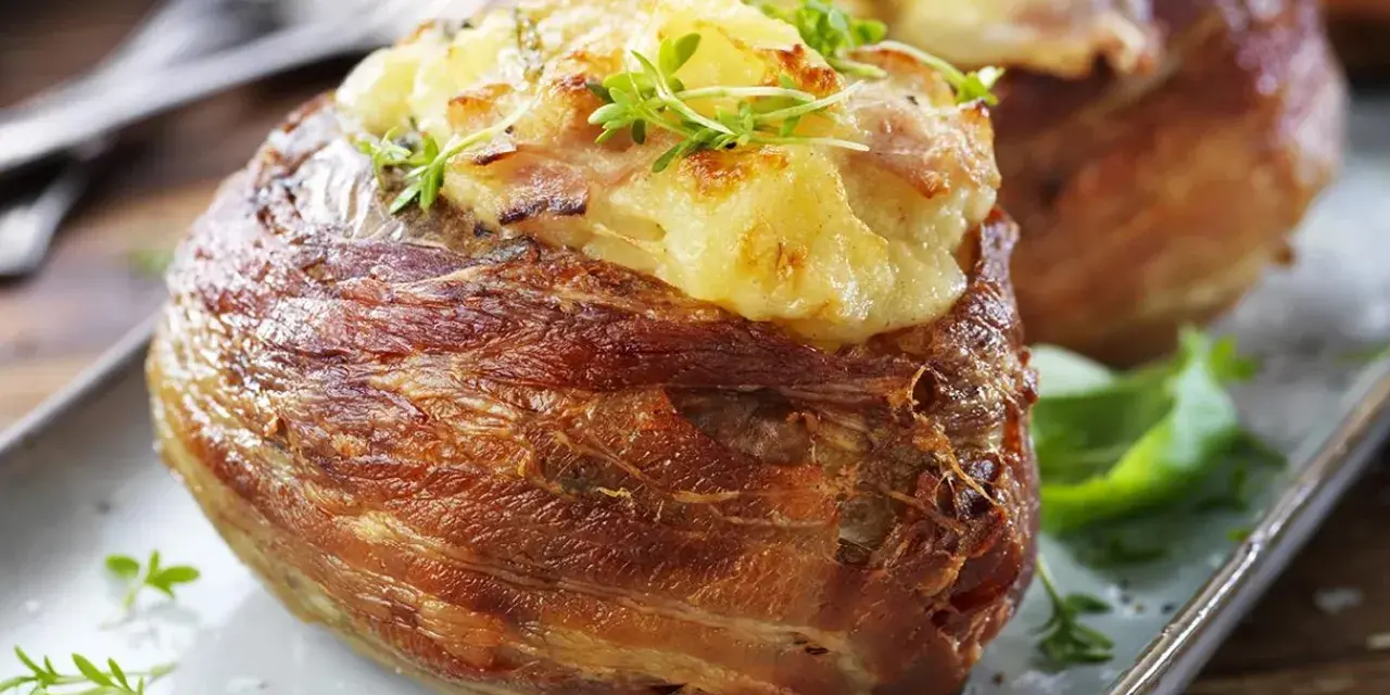 En härlig bakad potatis insvept i knaperstekt bacon, toppad med ost och örter. En riktig delikatess!