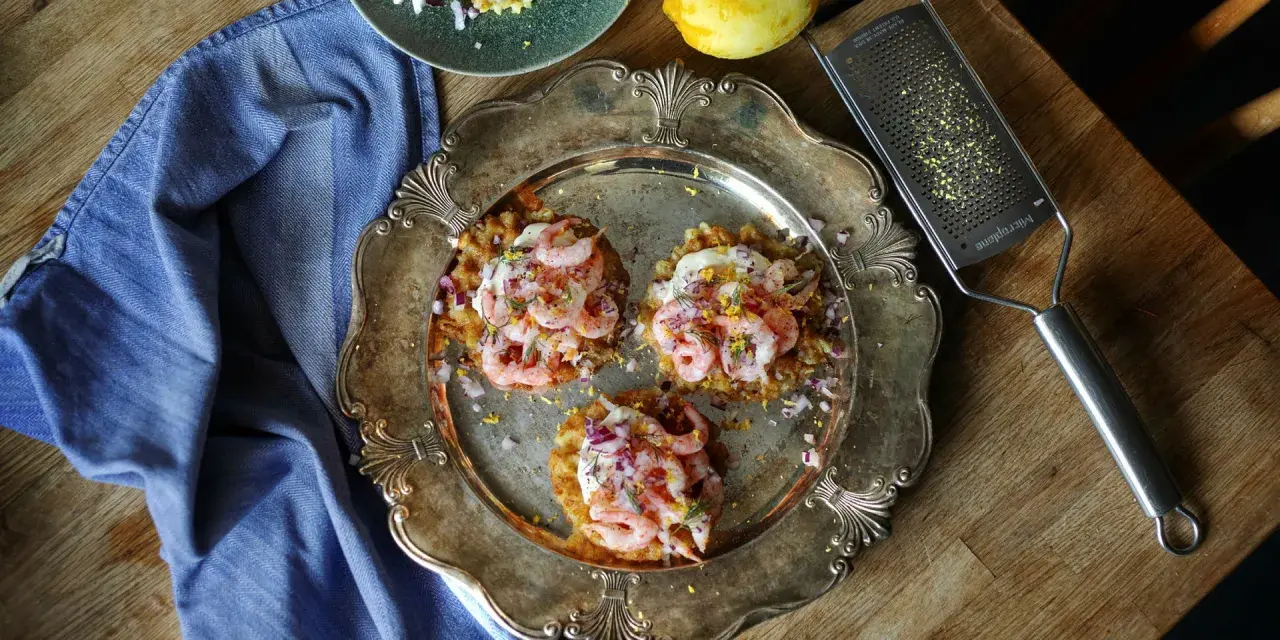 Tre potatisbullar med räkor, rödlök och dill på en silverbricka. Ett recept på potatisbullar som ser utsökt ut!