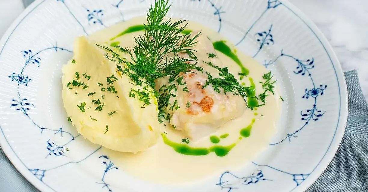 En vacker tallrik med torskrygg recept, serverad med krämigt potatismos och en grön dillolja.