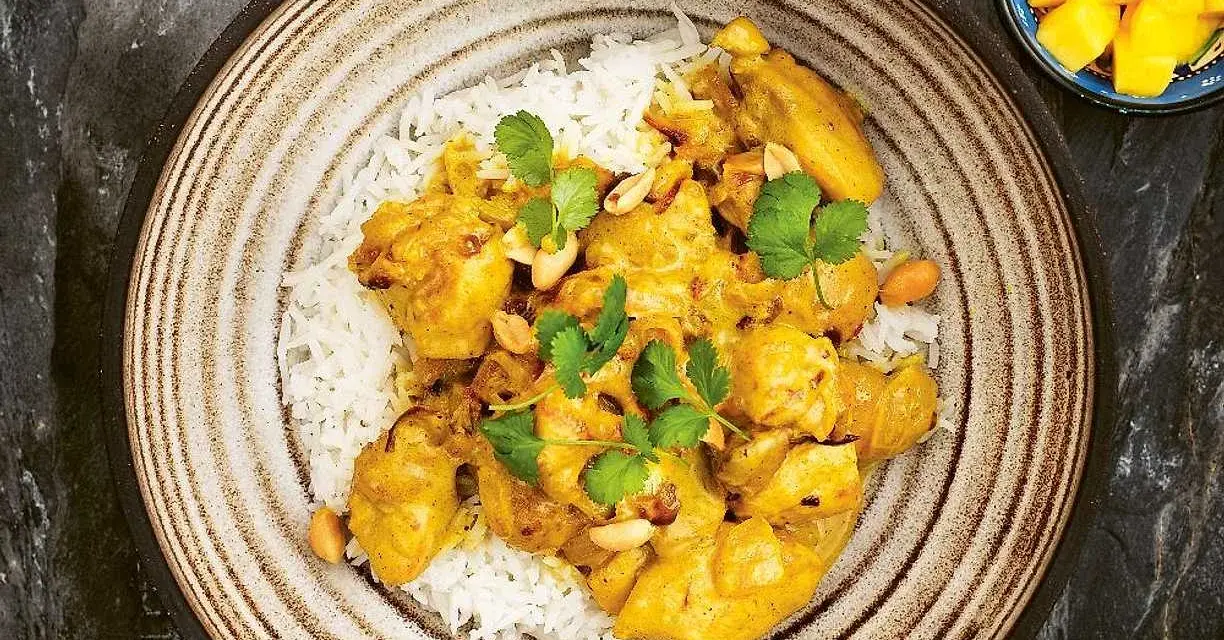 En krämig kycklingcurry med ris, toppad med koriander och jordnötter. En riktig curry nam nam!