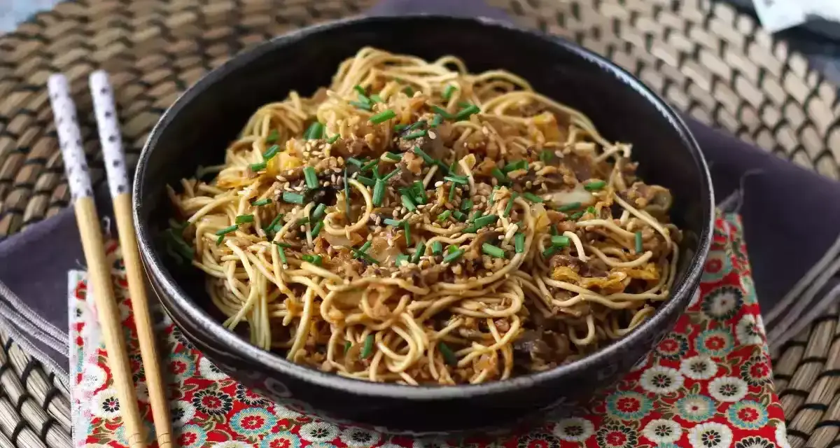 En skål med nudlar, köttfärs och grönsaker, toppad med sesamfrön och gräslök. Ett perfekt wok recept för en snabb middag.