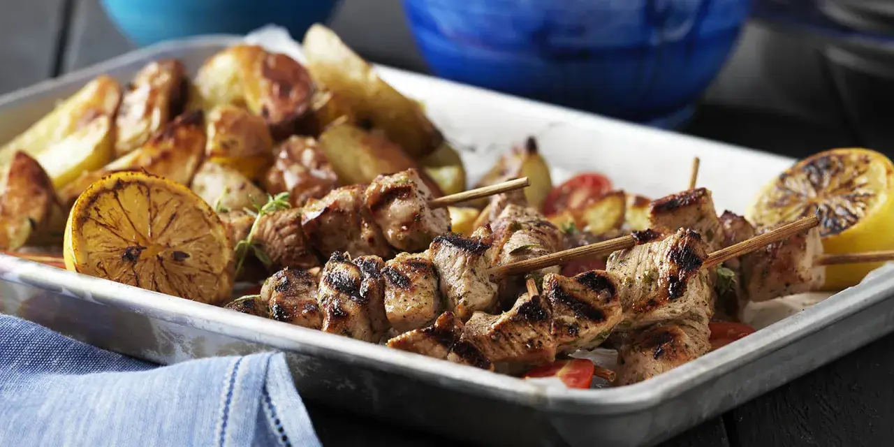 Grillade souvlaki-spett med rostade potatisar och citronklyftor. Ett perfekt souvlaki recept för en härlig middag.