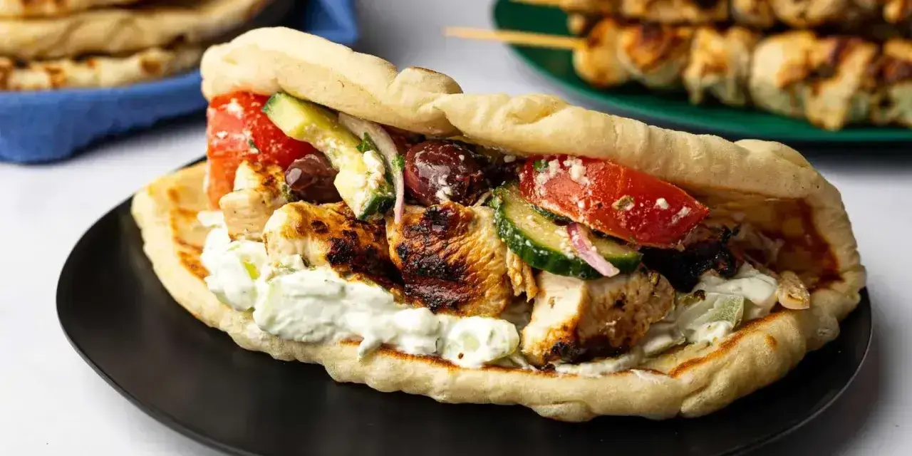 En saftig gyros med grillspett, tzatziki, tomat, gurka och oliver i pitabröd. Perfekt för ett snabbt grillspett recept.