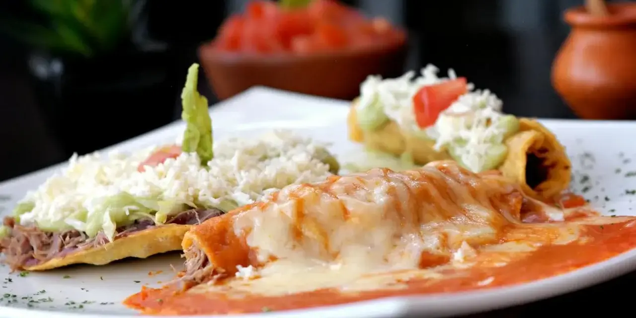 Enchiladas och en tostad med ost, guacamole och kött. En härlig tallrik med mexikansk mat som ser utsökt ut.