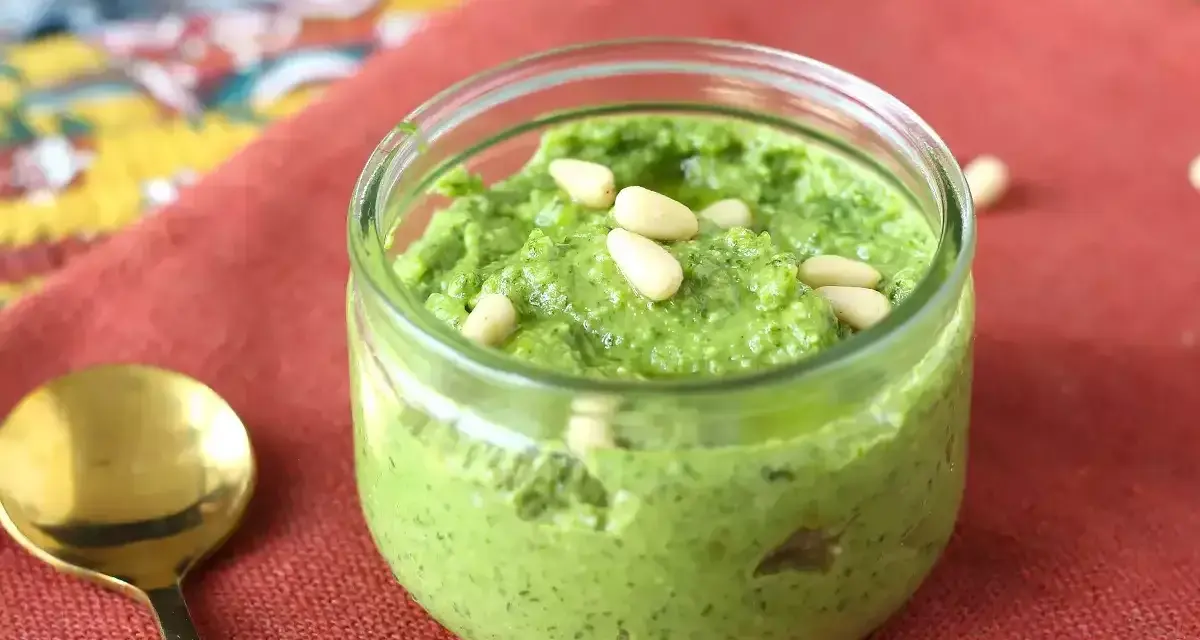En burk med hemgjord pesto, toppad med pinjenötter. Perfekt för ditt nästa pesto recept!