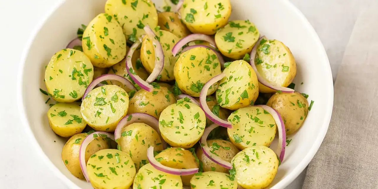 En skål med fransk potatissallad, full av små, kokta potatisar, rödlök och färsk persilja. En klassiker som passar till det mesta.