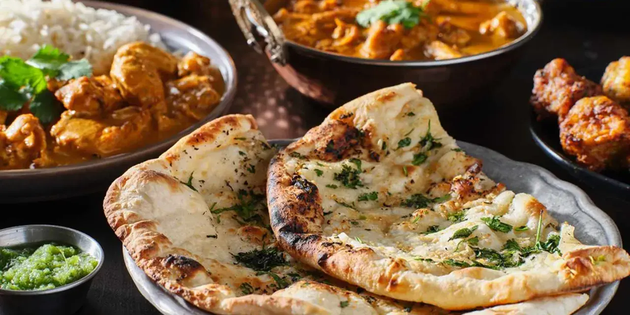 En härlig måltid med indisk mat, inklusive naanbröd, kycklingcurry och ris. Perfekt för en kväll med vin till indisk mat.