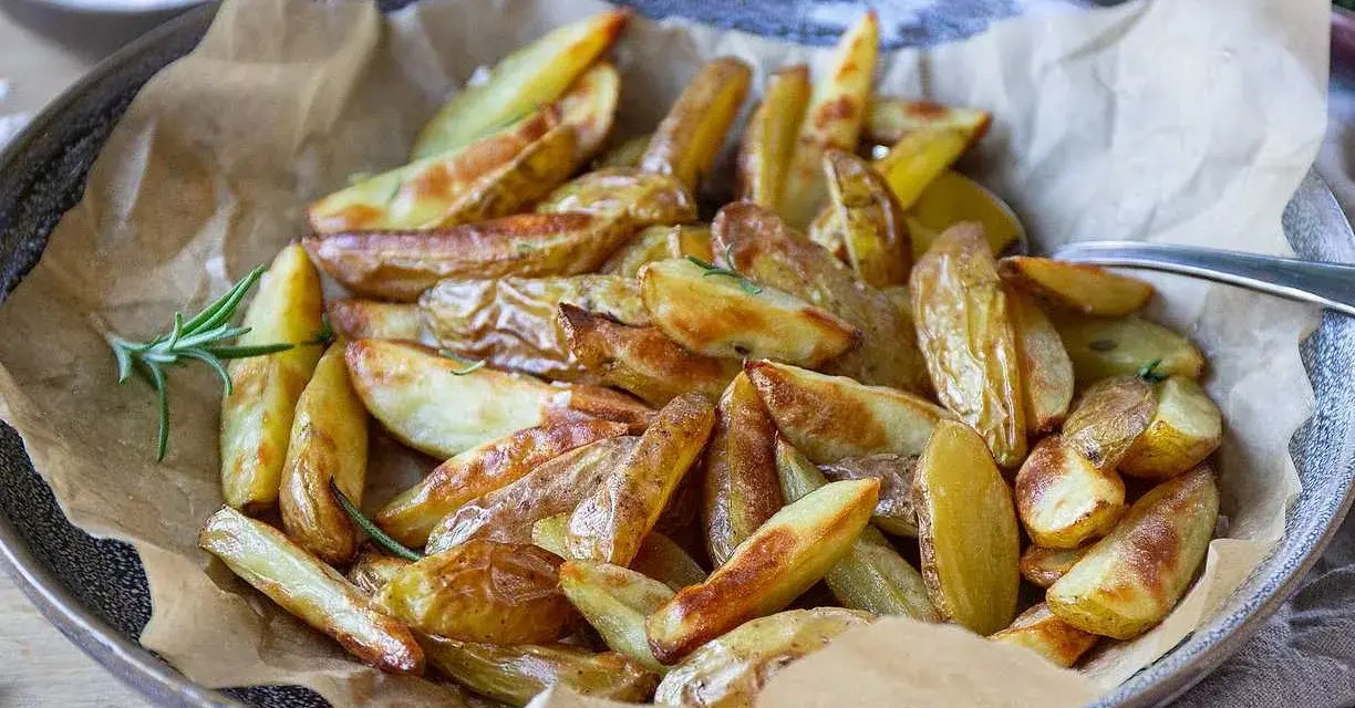 Klyftpotatis i airfryer, gyllene och krispiga, serverade med rosmarin. Perfekt tillbehör!