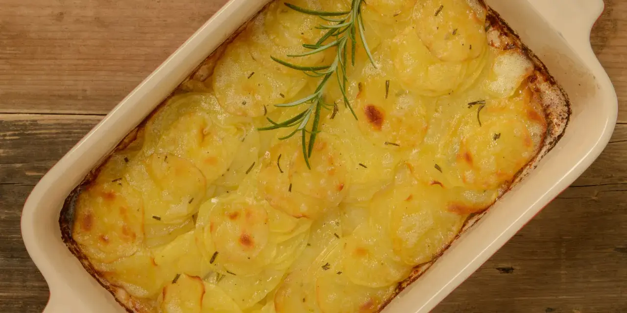 En ugnsform med gyllene, tunna potatisskivor, en klassisk pommes anna, toppad med en rosmarinkvist.
