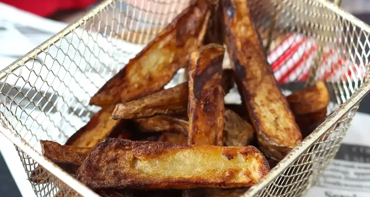 Krispiga pommes frites i airfryer, gyllene och redo att serveras i en metallkorg.