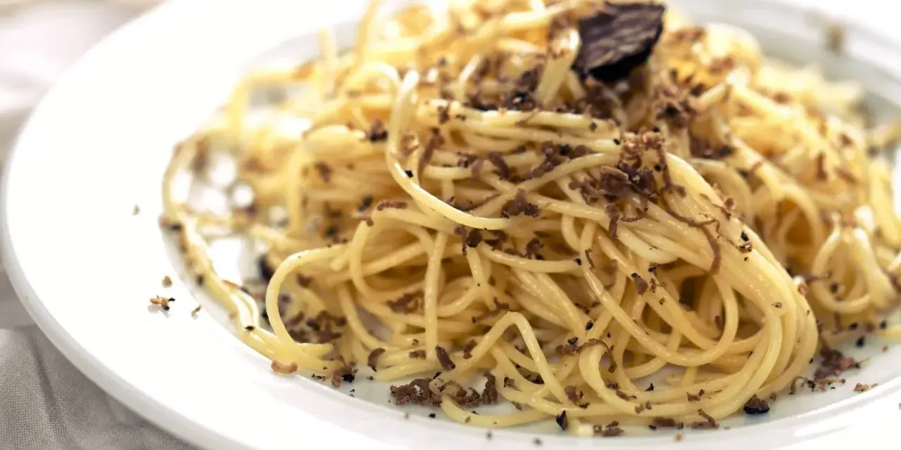 En tallrik med spaghetti toppad med rikligt med riven tryffel. Perfekt för en lyxig middag med ett gott vin till tryffelpasta.
