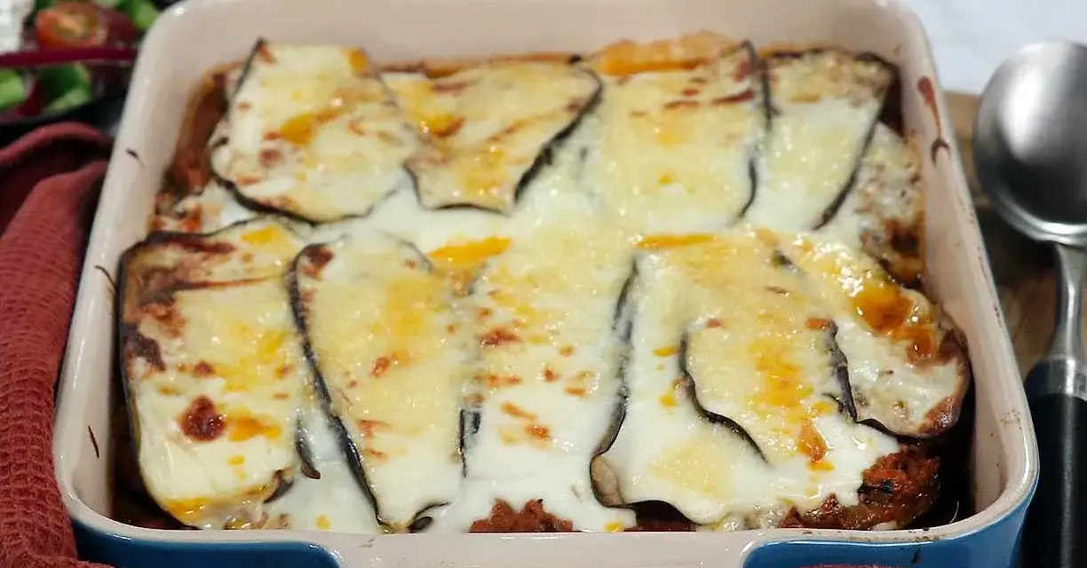 En ugnsform med en gyllene, bubblande moussaka, redo att serveras. Perfekt för ett mysigt middagsrecept.
