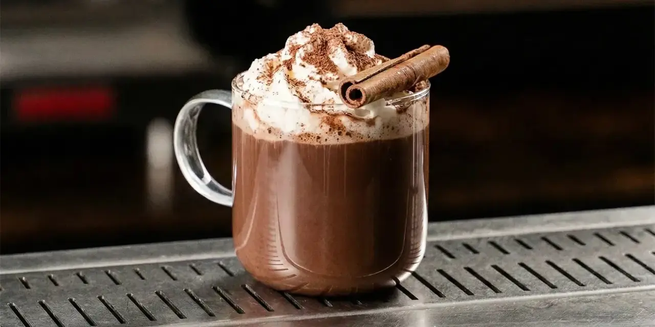Varm choklad med vispgrädde och kanelstång. En härlig dryck med intressant **lumumba drink ursprung**.
