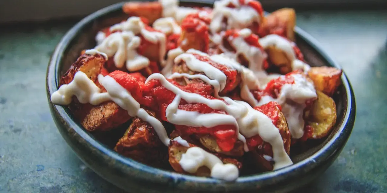 En skål med krispiga patatas bravas, toppade med en kryddig tomatsås och krämig aioli.