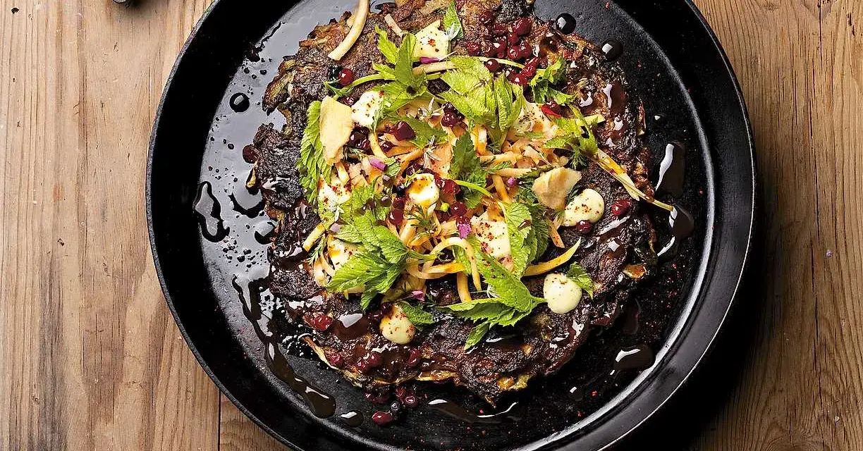 En mörk, krispig pannkaka med kirskål, toppad med färska örter, granatäppelkärnor och en krämig dressing. Ett spännande kirskål recept!