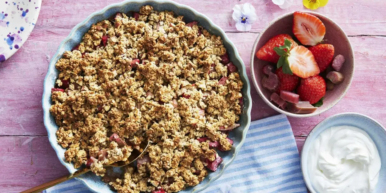 En härlig gammaldags rabarberpaj med krispigt täcke, serverad med färska jordgubbar och grädde. Perfekt sommardessert!