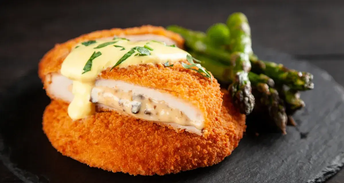 Krispig cordon bleu med krämig fyllning och hollandaisesås, serverad med sparris.