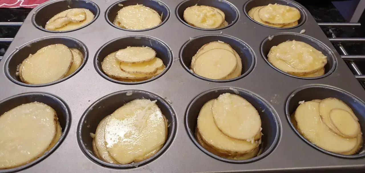 Tunna skivor av potatis i muffinsform, redo att bakas. Enkel och god rätt.