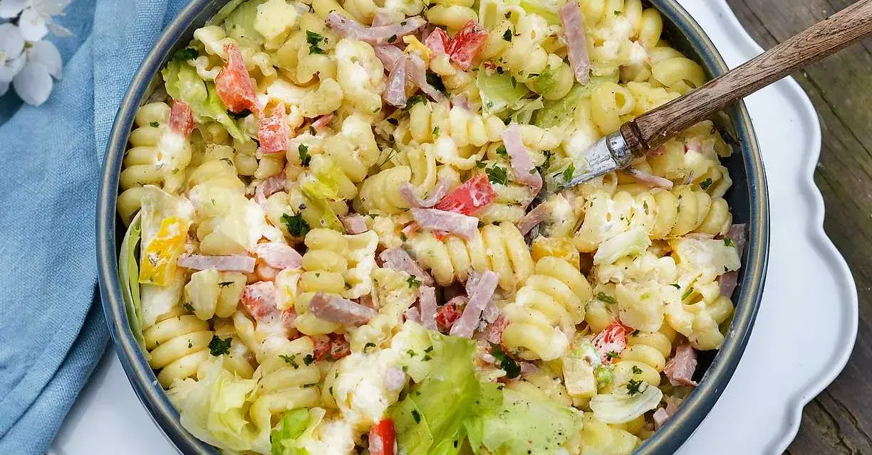 En krämig pastasallad med skinka, grönsaker och en dressing baserad på olja. Perfekt till sommaren!