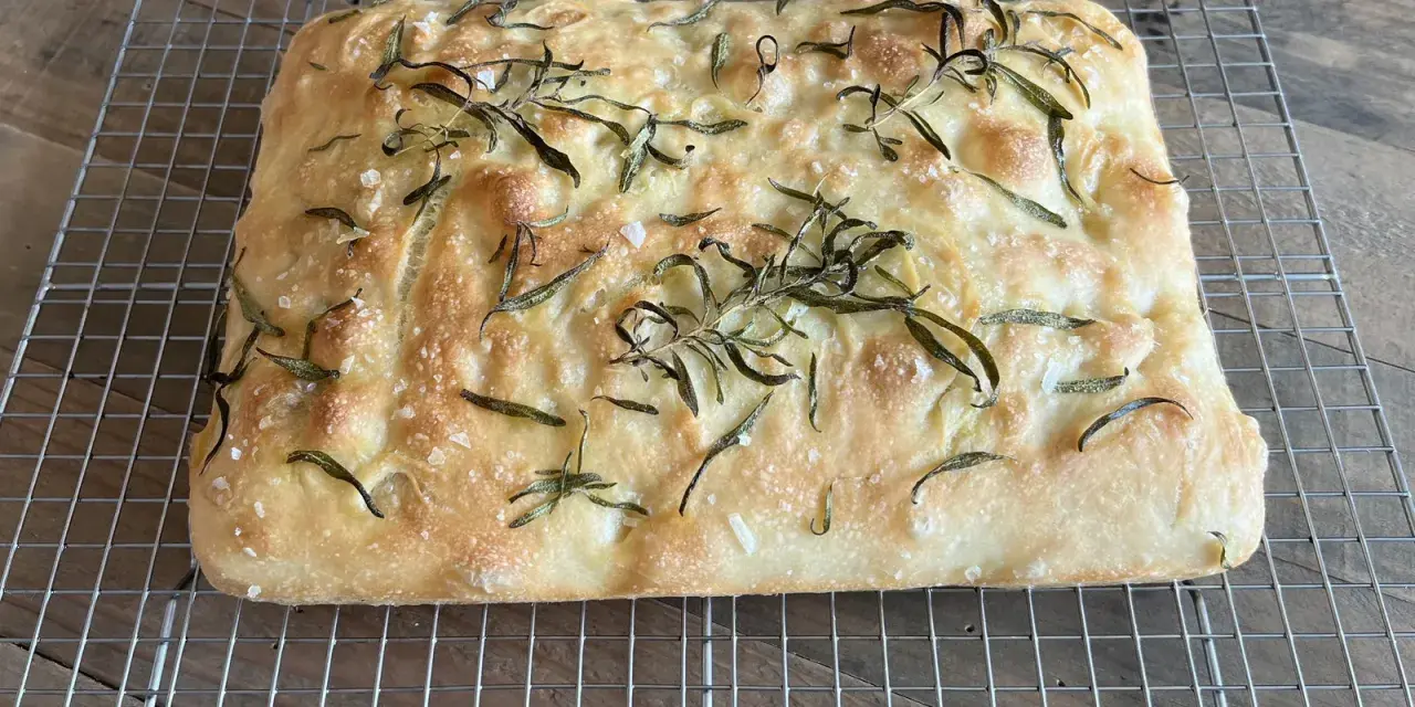 En gyllene, nybakad focaccia med rosmarin och flingsalt, perfekt för ditt nästa focaccia recept.