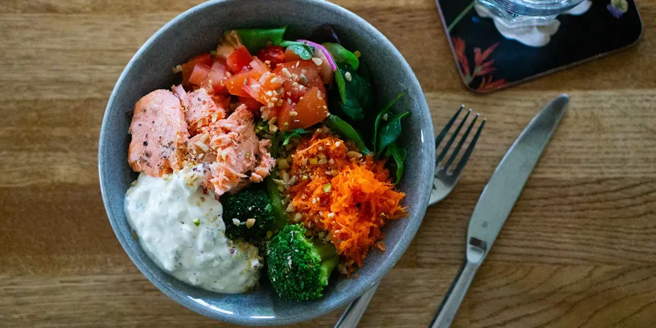 En härlig poke bowl med lax, broccoli, tomat, rivna morötter och en krämig sås. Perfekt för en hälsosam lunch.