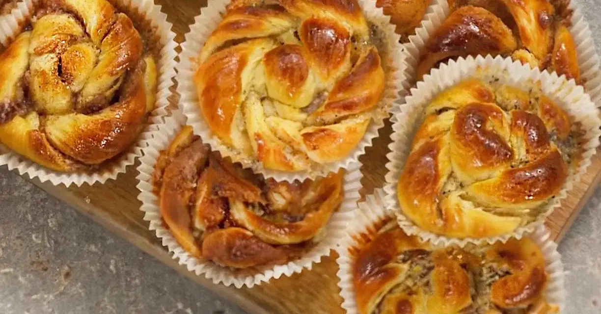 Nybakade bullar med mandelmassa och vallmofrön, gyllene och glansiga i sina pappersformar.